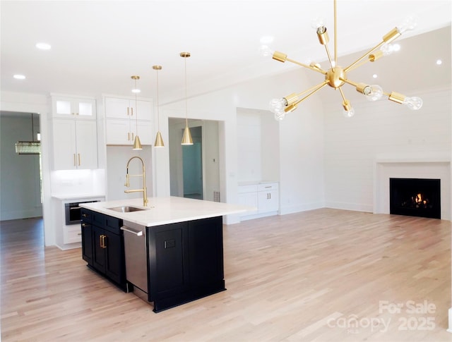 kitchen featuring stainless steel dishwasher, an inviting chandelier, white cabinetry, a sink, and open floor plan