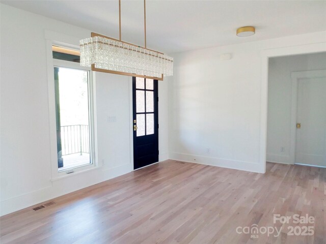interior space featuring a chandelier, light wood-style floors, baseboards, and visible vents