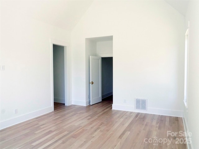 spare room featuring visible vents, baseboards, high vaulted ceiling, and light wood-style floors