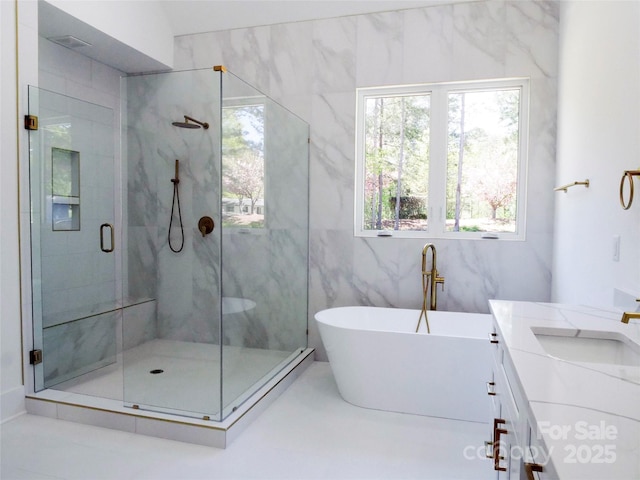 bathroom with a stall shower, vanity, a freestanding bath, and a wealth of natural light