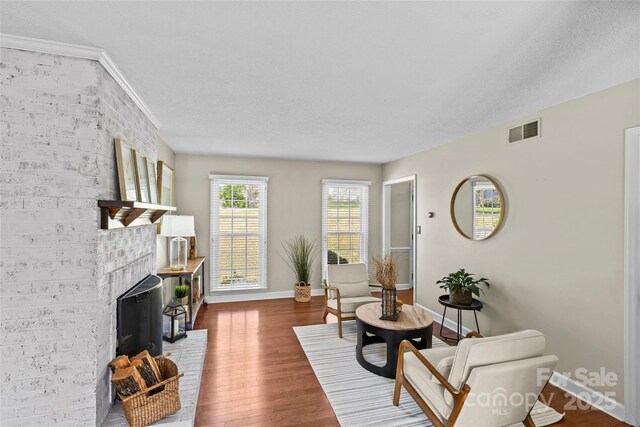living area featuring wood finished floors, a textured ceiling, baseboards, and visible vents