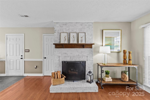 living room with visible vents, a textured ceiling, baseboards, and wood finished floors