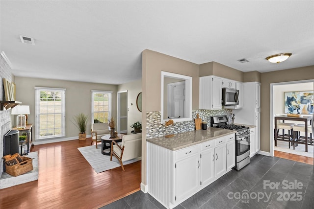 kitchen featuring white cabinetry, appliances with stainless steel finishes, backsplash, and visible vents