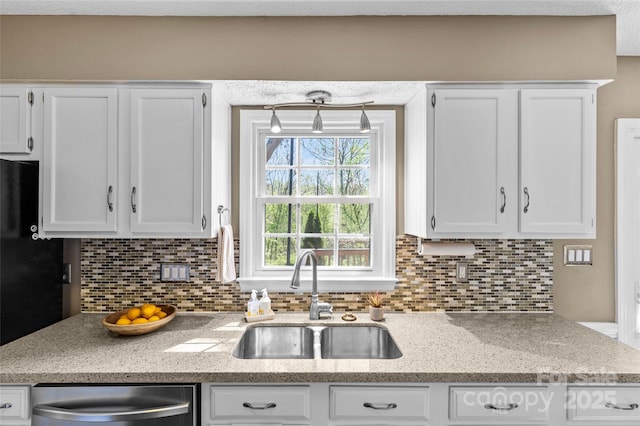 kitchen with decorative backsplash, white cabinets, a sink, and stainless steel dishwasher