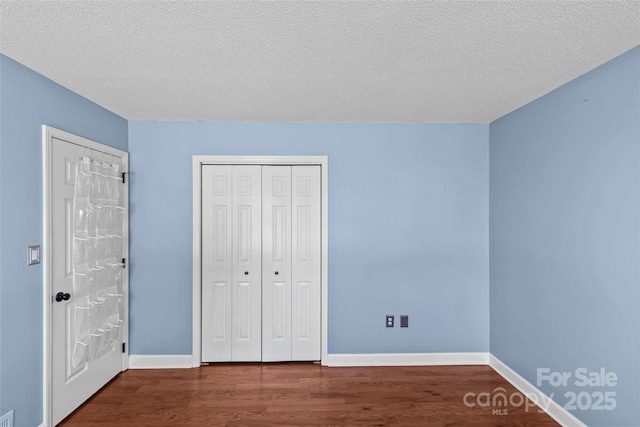 unfurnished bedroom featuring baseboards, a textured ceiling, and wood finished floors