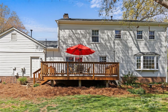 back of house featuring a wooden deck, a lawn, and a chimney