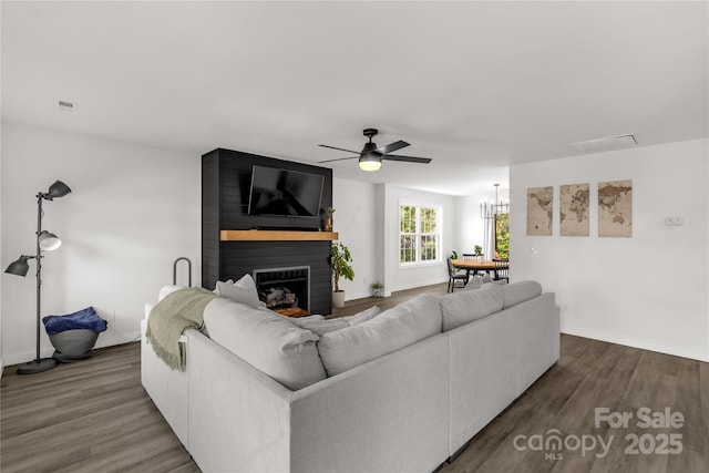 living room featuring a large fireplace, visible vents, baseboards, wood finished floors, and a ceiling fan