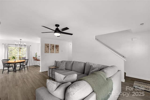 living room with ceiling fan with notable chandelier, wood finished floors, and baseboards