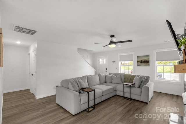 living area featuring baseboards, ceiling fan, visible vents, and wood finished floors