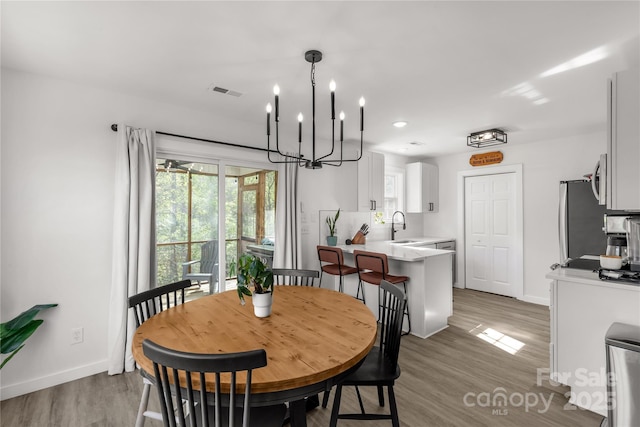 dining room with baseboards, a wealth of natural light, visible vents, and wood finished floors