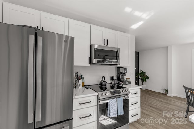 kitchen featuring light countertops, backsplash, light wood-type flooring, and appliances with stainless steel finishes