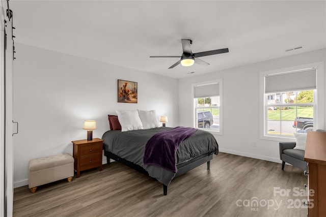 bedroom with baseboards, light wood-style floors, ceiling fan, and visible vents