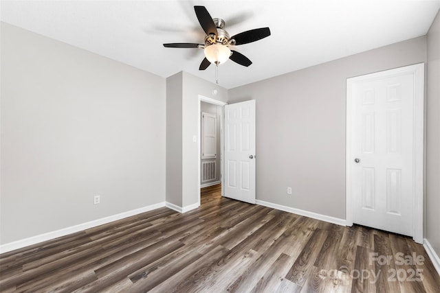 unfurnished bedroom with baseboards, ceiling fan, visible vents, and dark wood finished floors