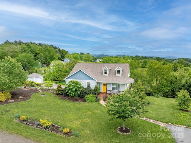 cape cod home with covered porch, an outdoor structure, roof with shingles, and a front lawn