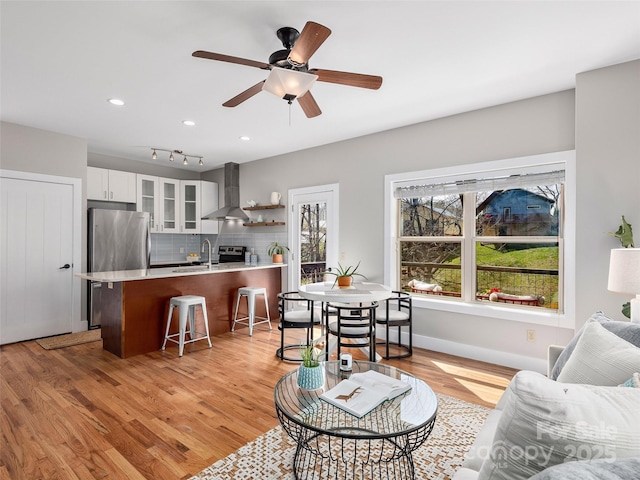 living area with light wood finished floors, baseboards, ceiling fan, and recessed lighting