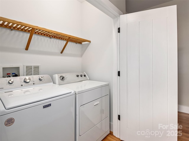clothes washing area featuring light wood-type flooring, baseboards, washing machine and clothes dryer, visible vents, and laundry area