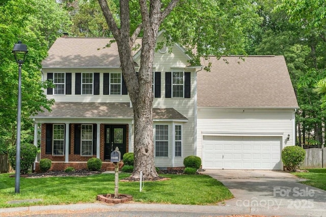 view of front of home with concrete driveway, an attached garage, a shingled roof, and a front yard