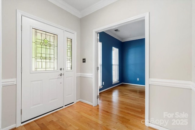 foyer entrance featuring light wood finished floors, baseboards, visible vents, and ornamental molding