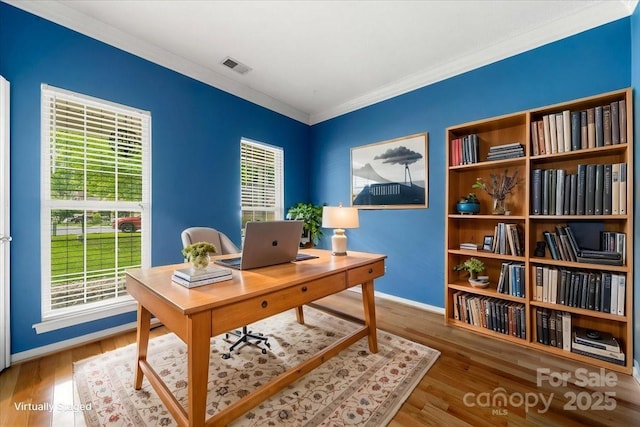 office featuring wood finished floors, visible vents, baseboards, and ornamental molding