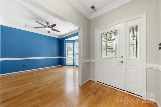 entrance foyer with light wood-type flooring, ceiling fan, baseboards, ornamental molding, and visible vents