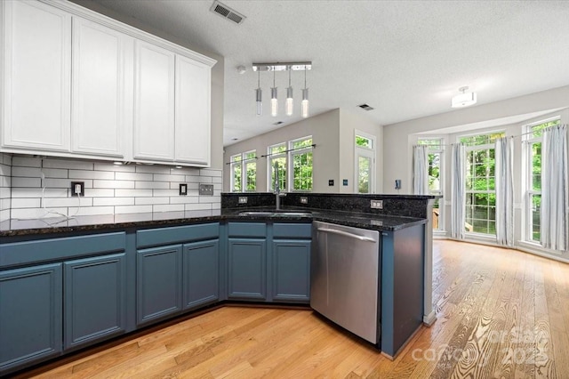 kitchen with stainless steel dishwasher, blue cabinets, light wood-type flooring, white cabinets, and visible vents