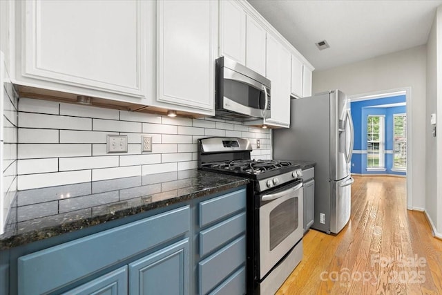 kitchen with blue cabinets, stainless steel appliances, light wood-style flooring, white cabinets, and visible vents