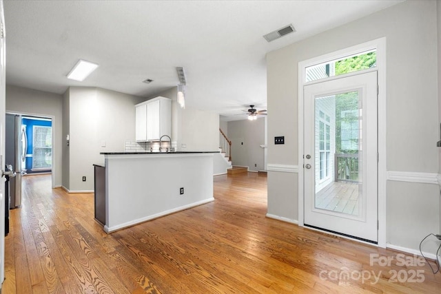 kitchen featuring dark countertops, a wealth of natural light, light wood-style flooring, white cabinets, and visible vents