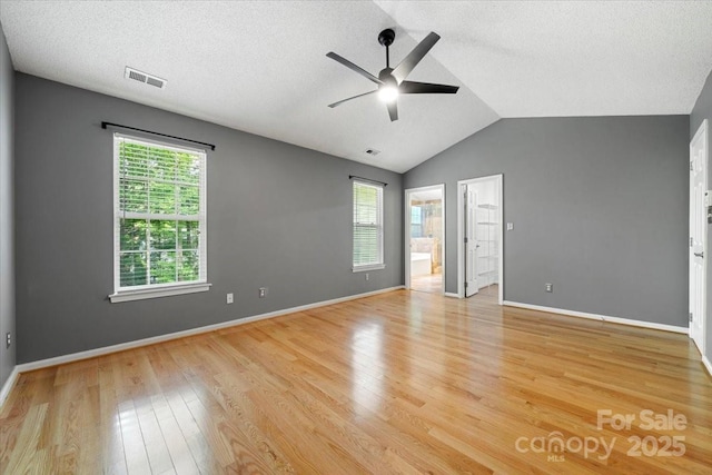 unfurnished bedroom with light wood-type flooring, visible vents, lofted ceiling, and multiple windows