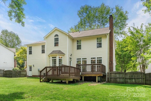 rear view of property with a chimney, a wooden deck, a yard, and a fenced backyard