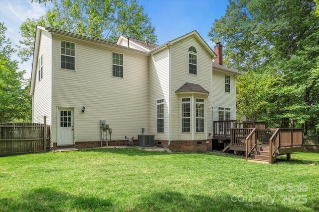 rear view of property featuring a wooden deck, a yard, a chimney, and fence