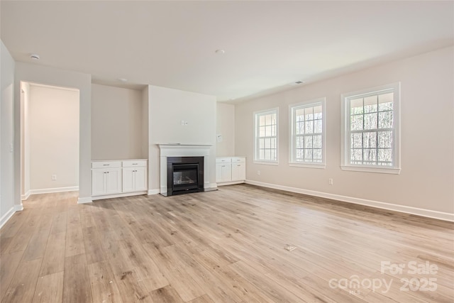 7005 New Town Rd, Waxhaw, NC 28173 - unfurnished living room featuring light wood finished floors, baseboards, and a glass covered fireplace