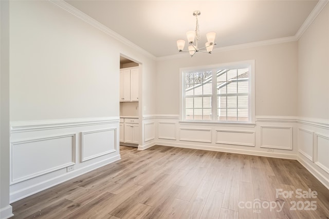 7005 New Town Rd, Waxhaw, NC 28173 - unfurnished dining area featuring a chandelier, light wood-type flooring, crown molding, and a wainscoted wall