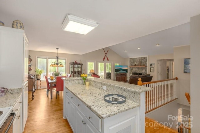 56 Lake Mist Ct Unit 30 & 30A, Nebo, NC 28761 - kitchen with a stone fireplace, vaulted ceiling, light wood-style flooring, white cabinetry, and a kitchen island