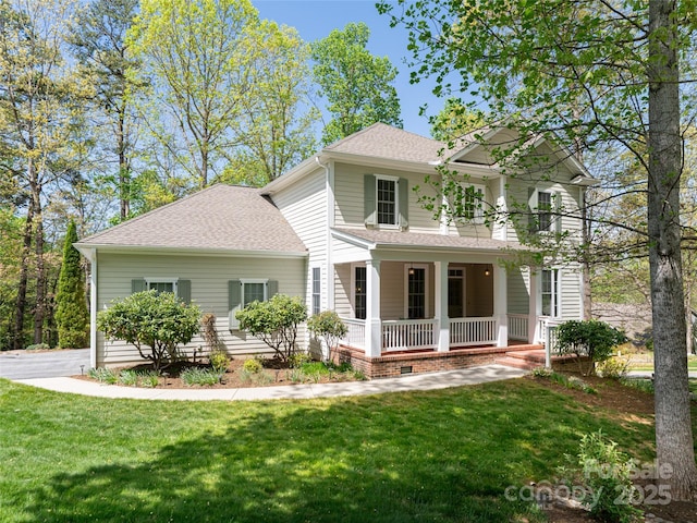 rear view of house with roof with shingles, a porch, and a lawn