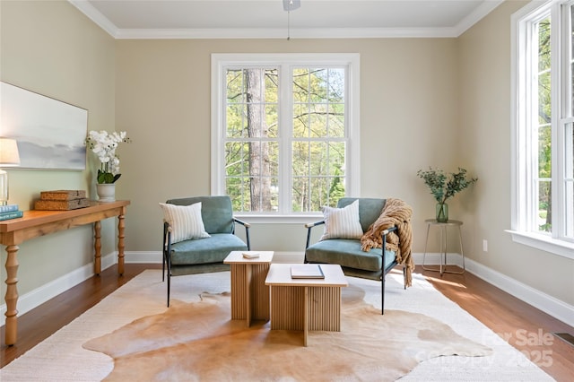 living area featuring baseboards, crown molding, and wood finished floors