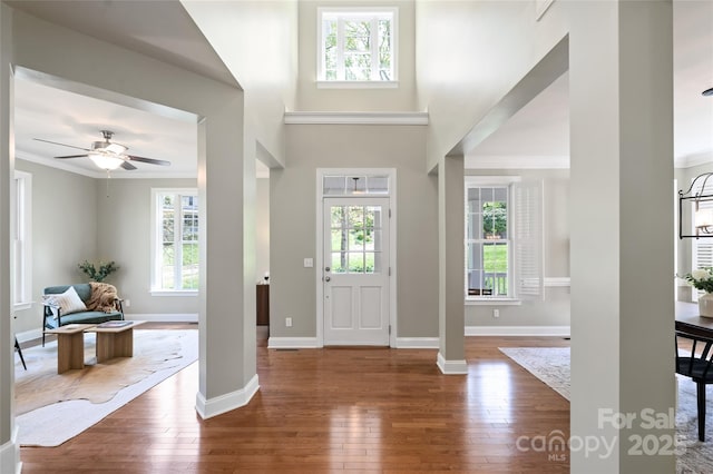 foyer entrance featuring crown molding, hardwood / wood-style floors, a ceiling fan, and baseboards