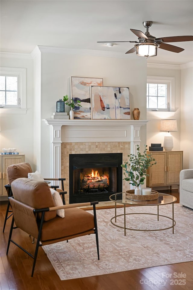 sitting room featuring a ceiling fan, wood finished floors, a fireplace, and crown molding