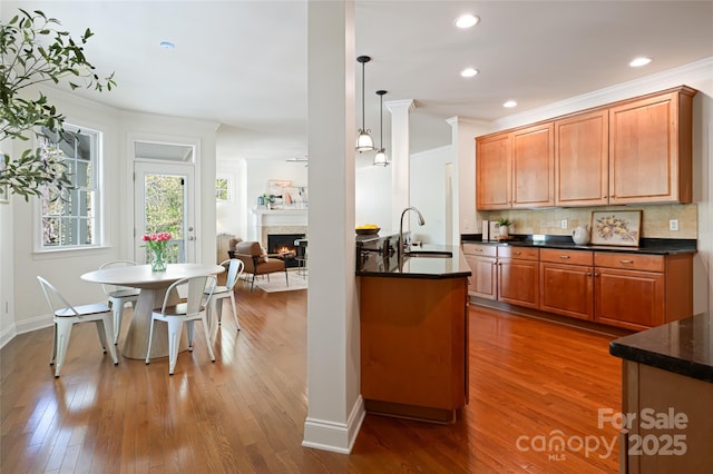 kitchen featuring wood finished floors, a sink, backsplash, ornamental molding, and recessed lighting