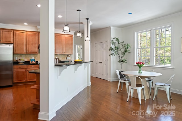 kitchen with dark countertops, a breakfast bar, stainless steel fridge, and brown cabinets