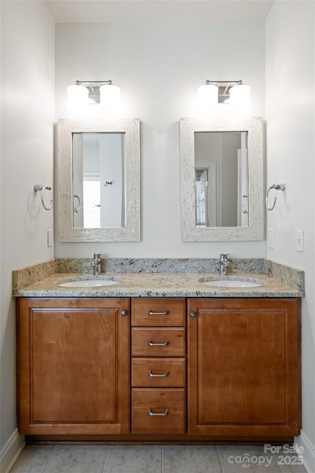 bathroom with double vanity, baseboards, and a sink