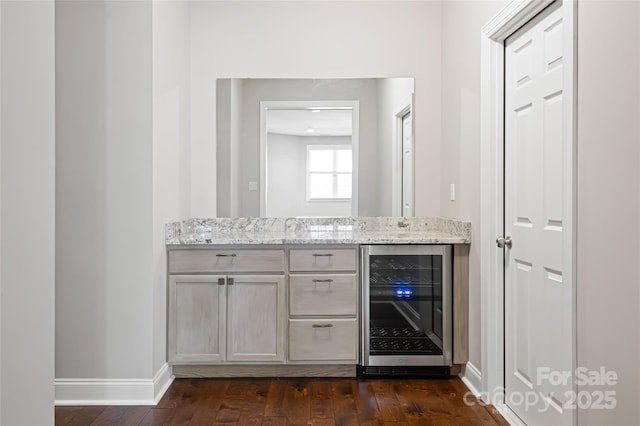 bar featuring baseboards, beverage cooler, and dark wood-type flooring