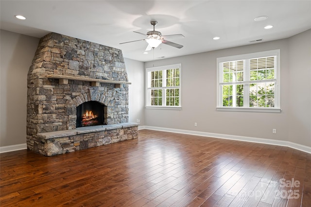 unfurnished living room with baseboards, visible vents, a fireplace, and wood-type flooring