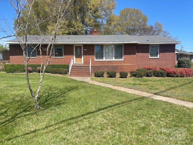 single story home with brick siding, a front lawn, and a chimney