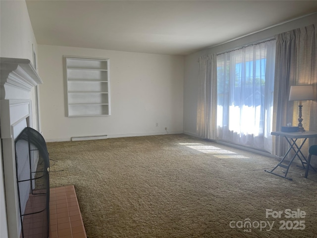 unfurnished living room featuring a fireplace, carpet flooring, baseboards, and built in shelves