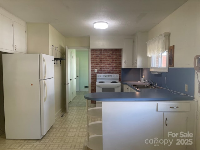 kitchen with white appliances, light floors, a peninsula, white cabinets, and a sink