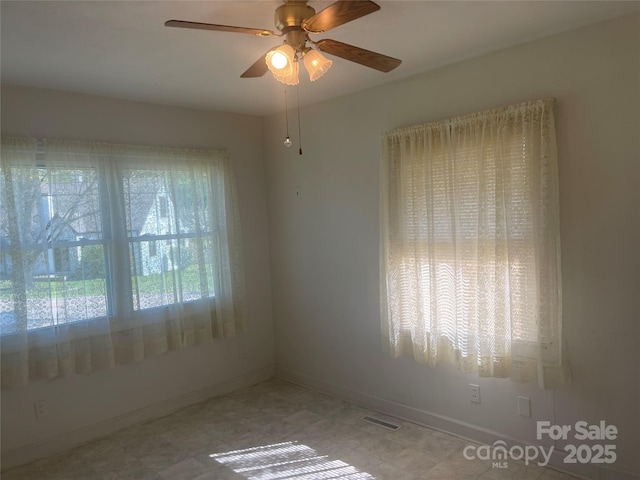 spare room featuring visible vents, baseboards, a ceiling fan, and a healthy amount of sunlight