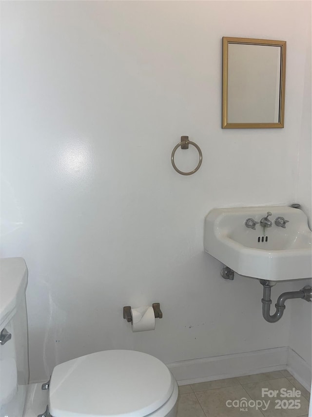 half bath featuring a sink, toilet, tile patterned flooring, and baseboards