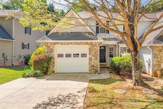 traditional-style house with an attached garage, driveway, a shingled roof, and stone siding