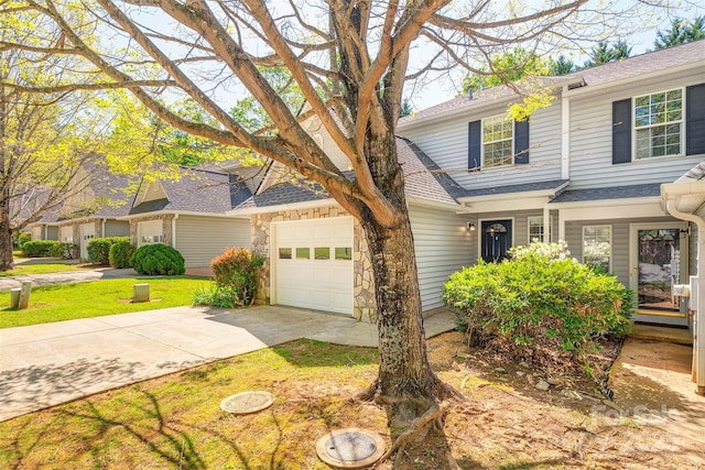 traditional-style house with roof with shingles, driveway, a front yard, and a garage