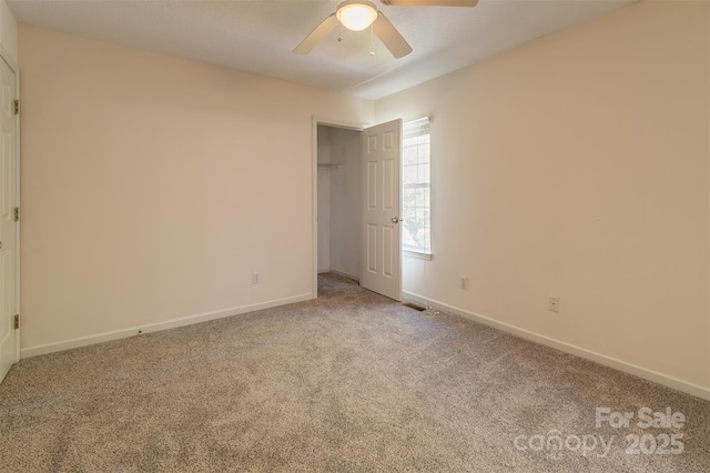 carpeted empty room featuring ceiling fan, visible vents, and baseboards